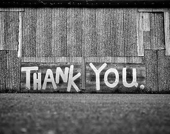 A black and white photo of a thank you sign on a wall.