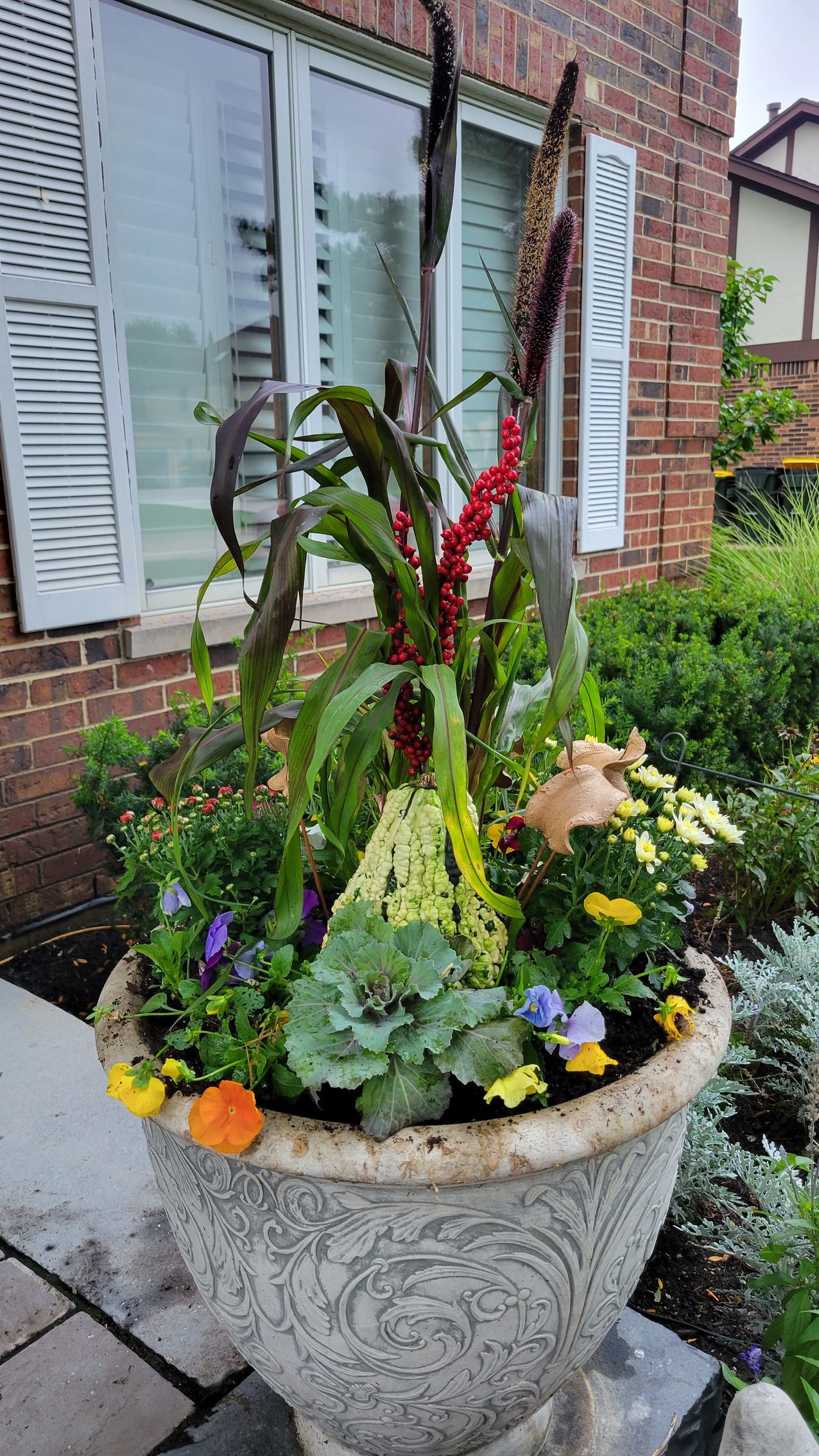 A planter filled with flowers is sitting in front of a brick building.