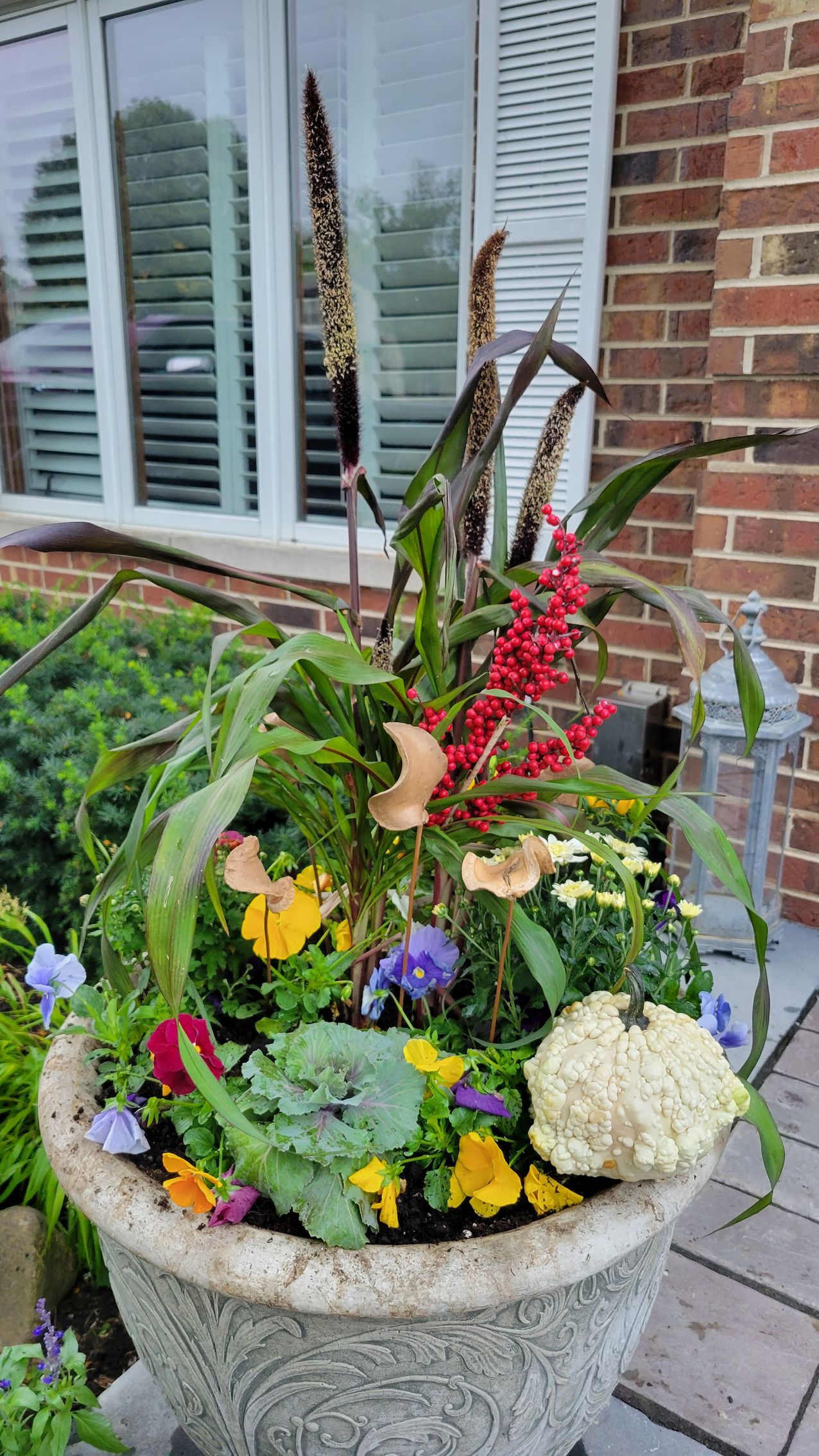 A planter filled with flowers is sitting in front of a brick building.