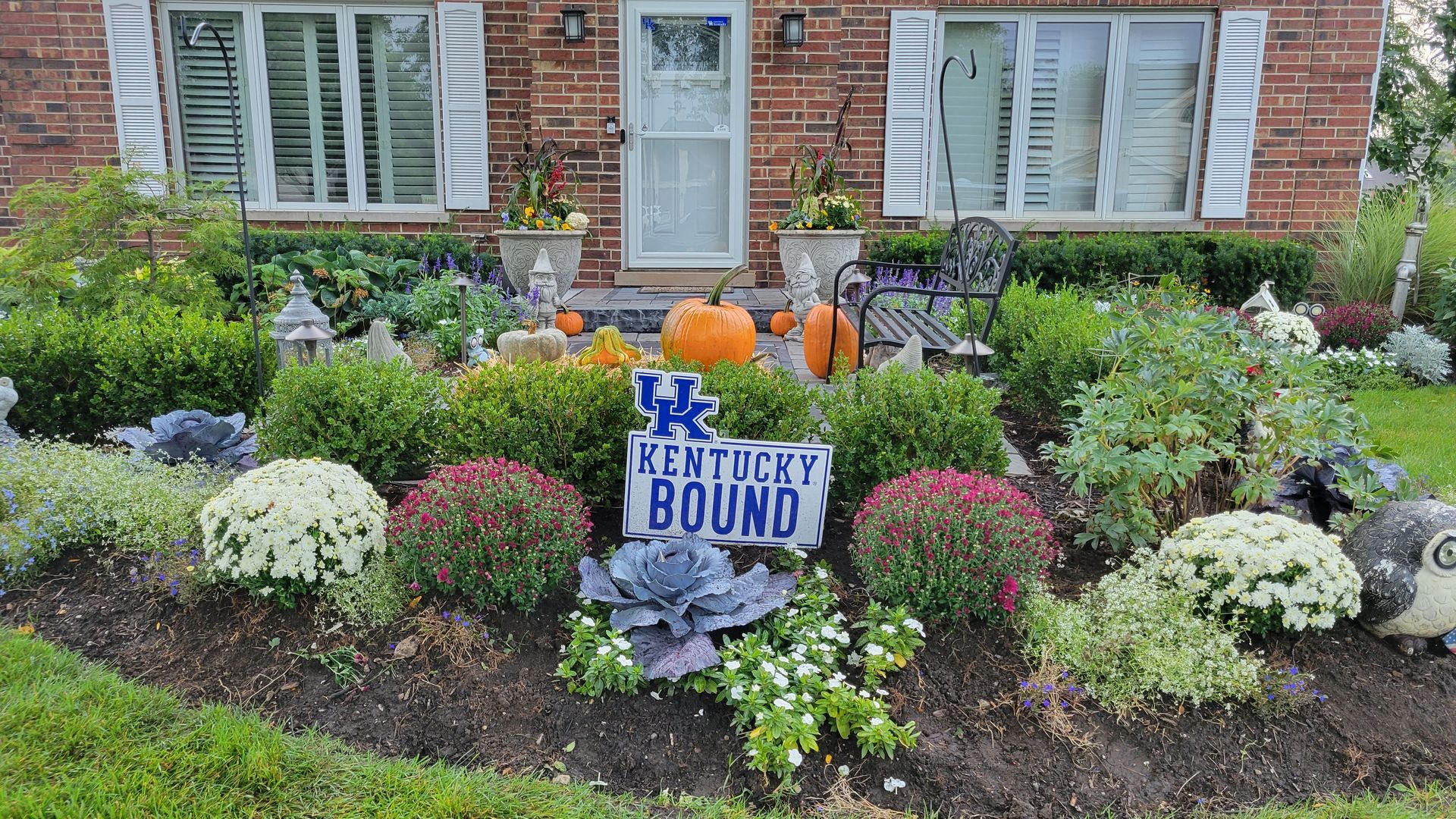 A garden with a sign that says kentucky bound in front of a brick house.