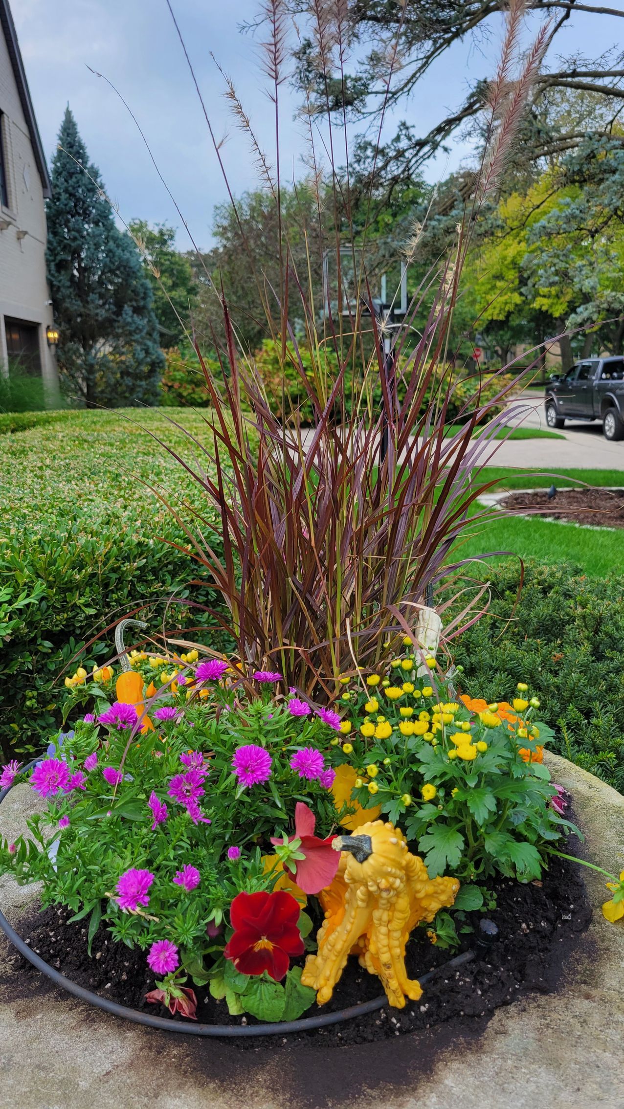 A planter filled with flowers and a statue of a parrot in a garden.
