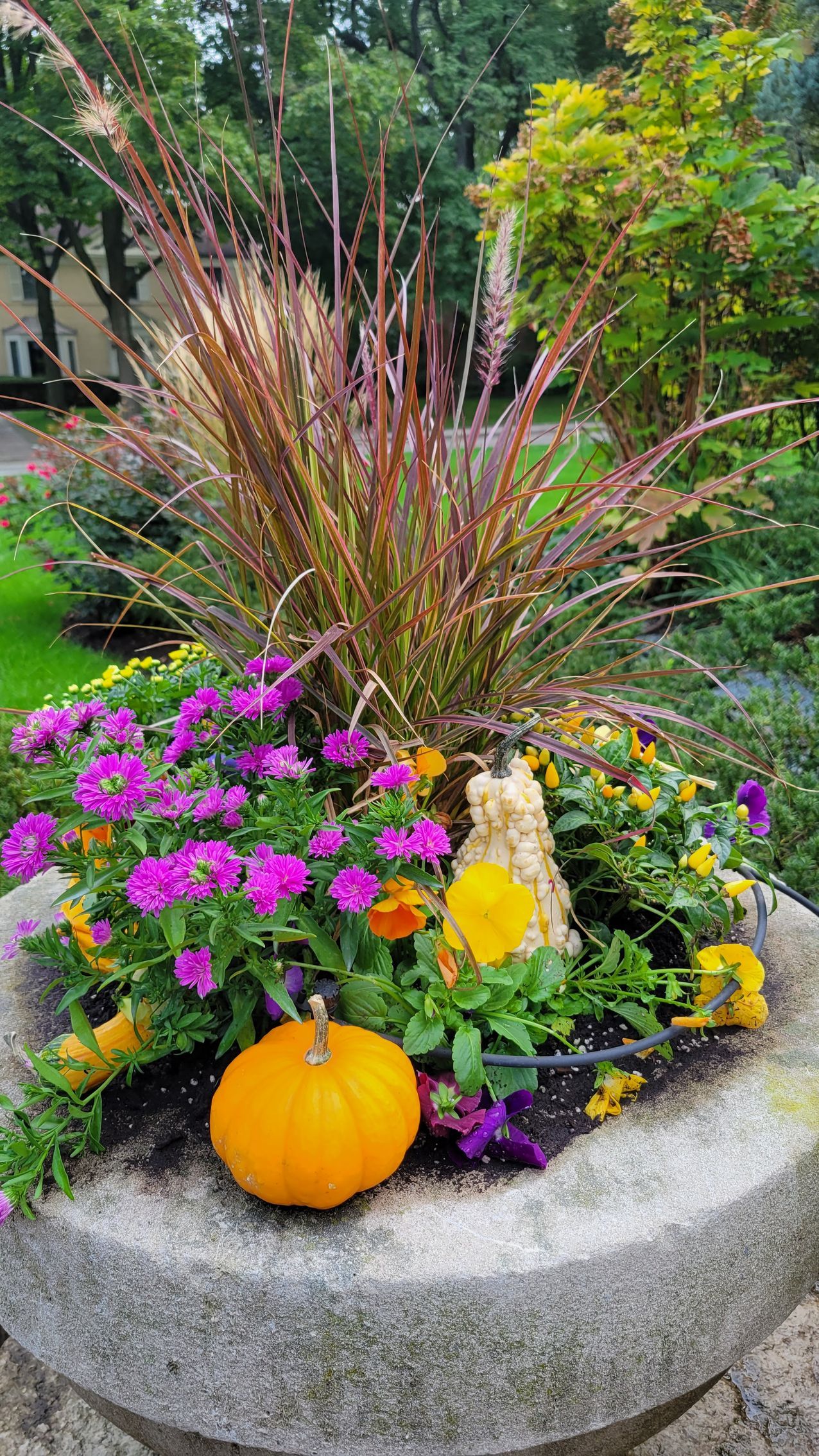 A planter filled with flowers and a pumpkin in a garden.