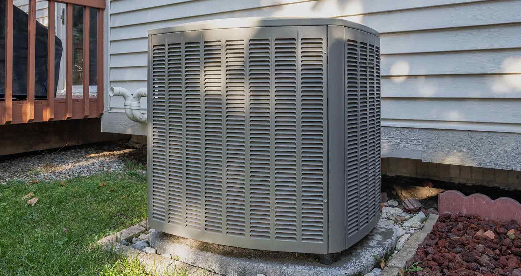 An air conditioner is sitting on the side of a house.