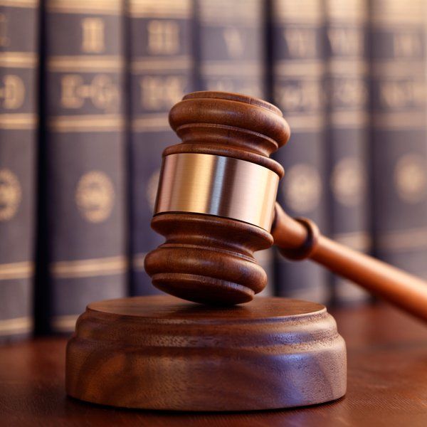 Wooden gavel resting on a block in front of law books.
