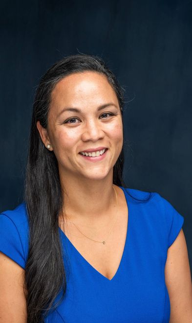 A woman in a blue shirt is smiling for the camera.