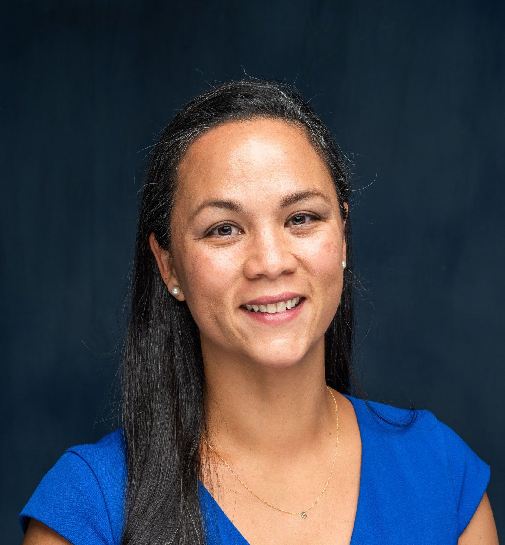 A woman in a white lab coat is smiling for the camera.