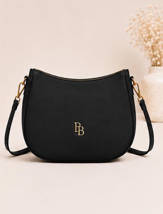 Black monogram handbag with gold hardware and shoulder strap on a light background