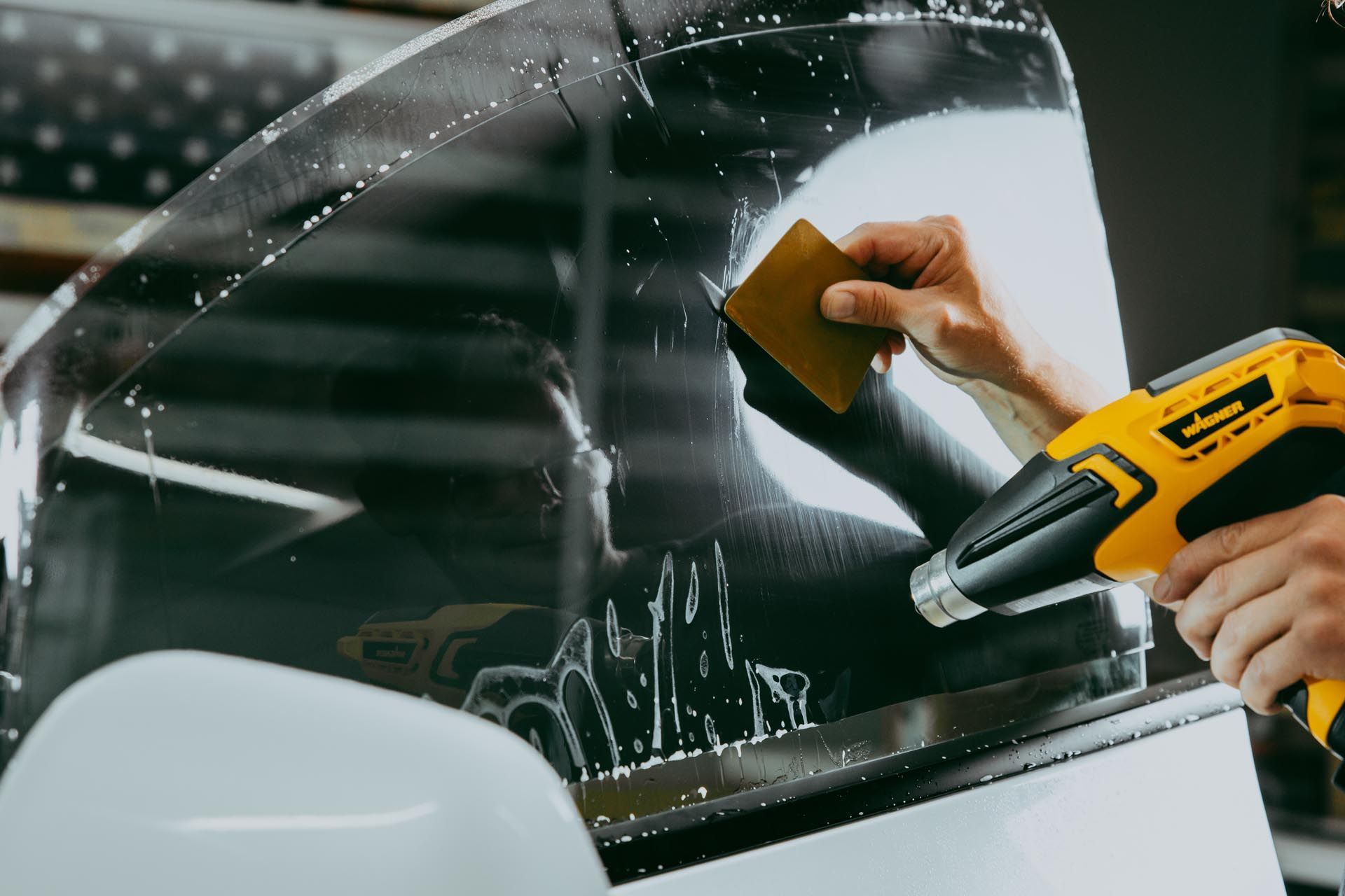 A man is applying tinted glass to a car window.