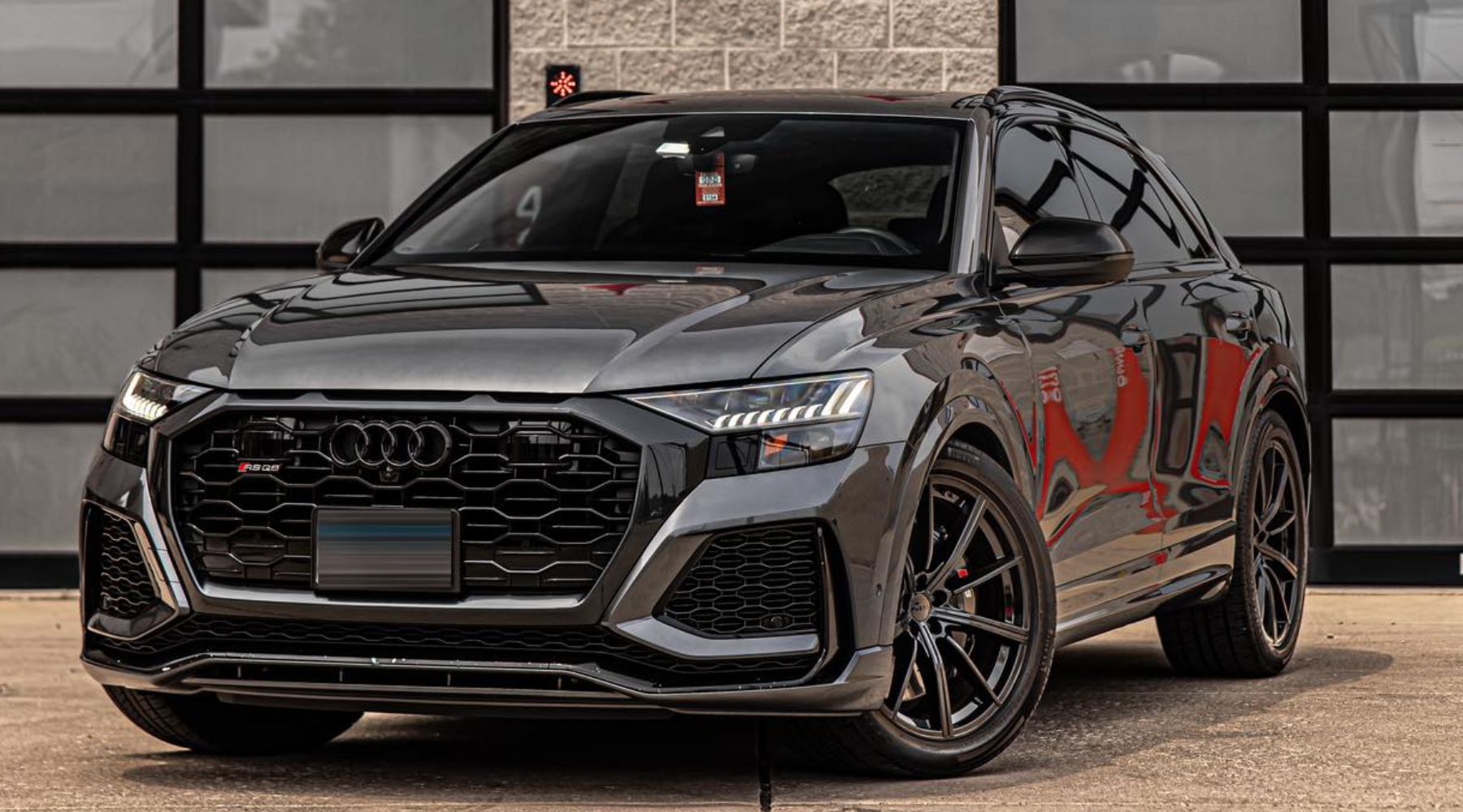 A sleek, black Audi RS Q8 parked in front of a modern garage, with a glossy ceramic-coated finish re