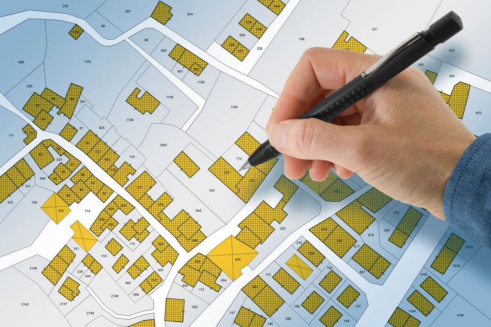 Mano che traccia con una penna una mappa dettagliata della proprietà, evidenziando in giallo i lotti edificabili.