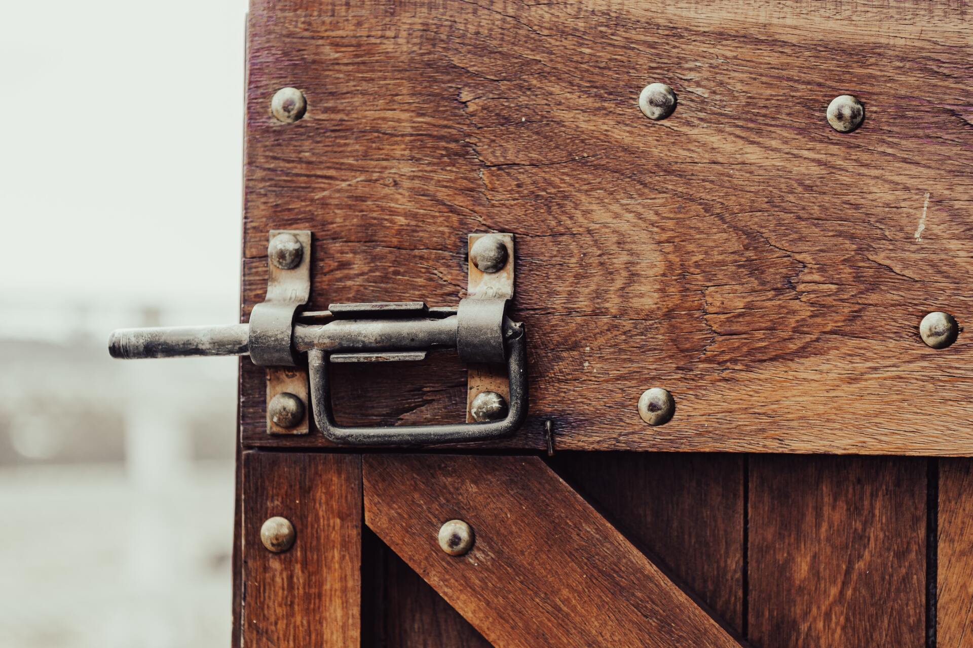 Wooden barn door with latch that is open and screws in the wood