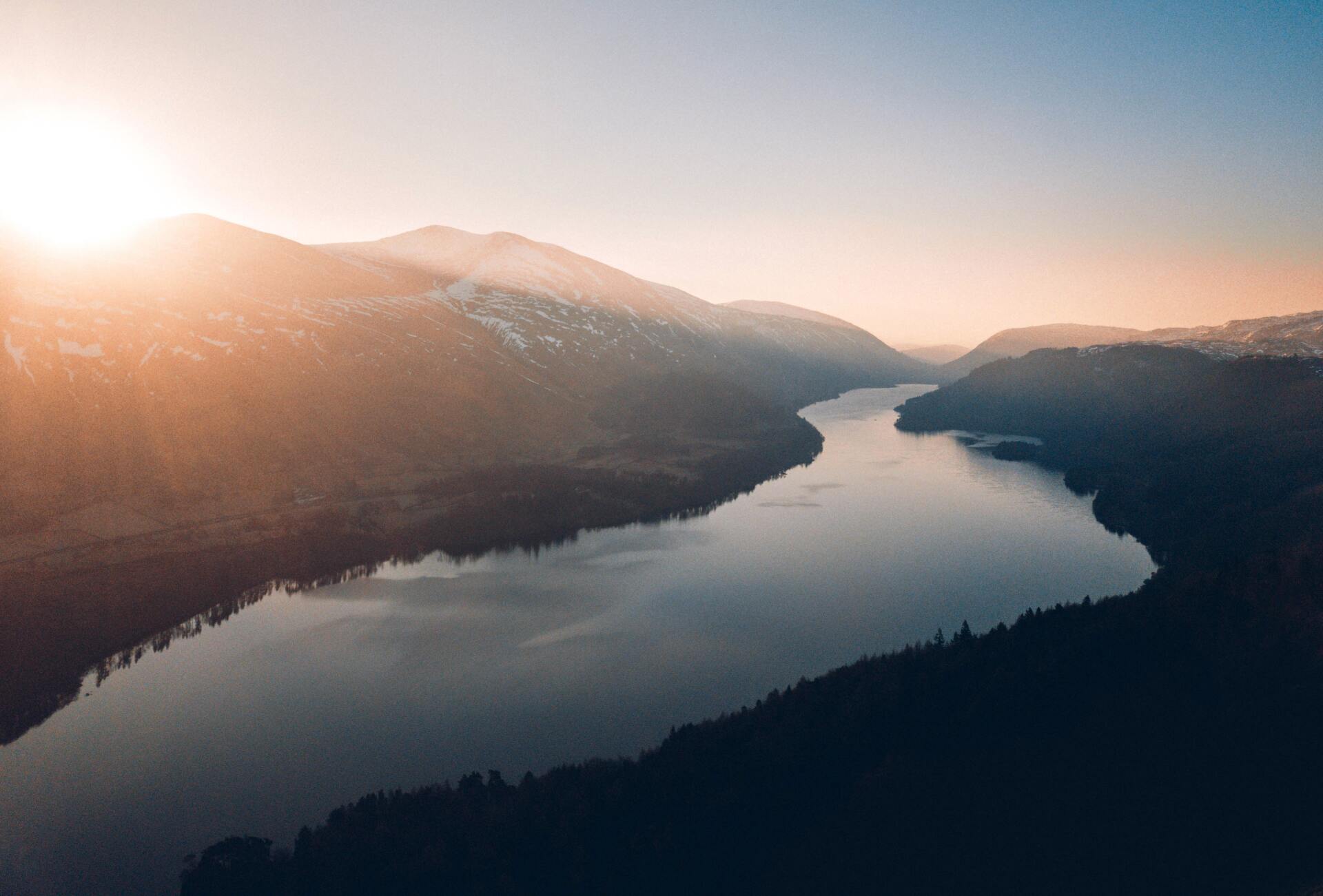 River flowing through the mountains with trees on both sides of the forest and the sun rising