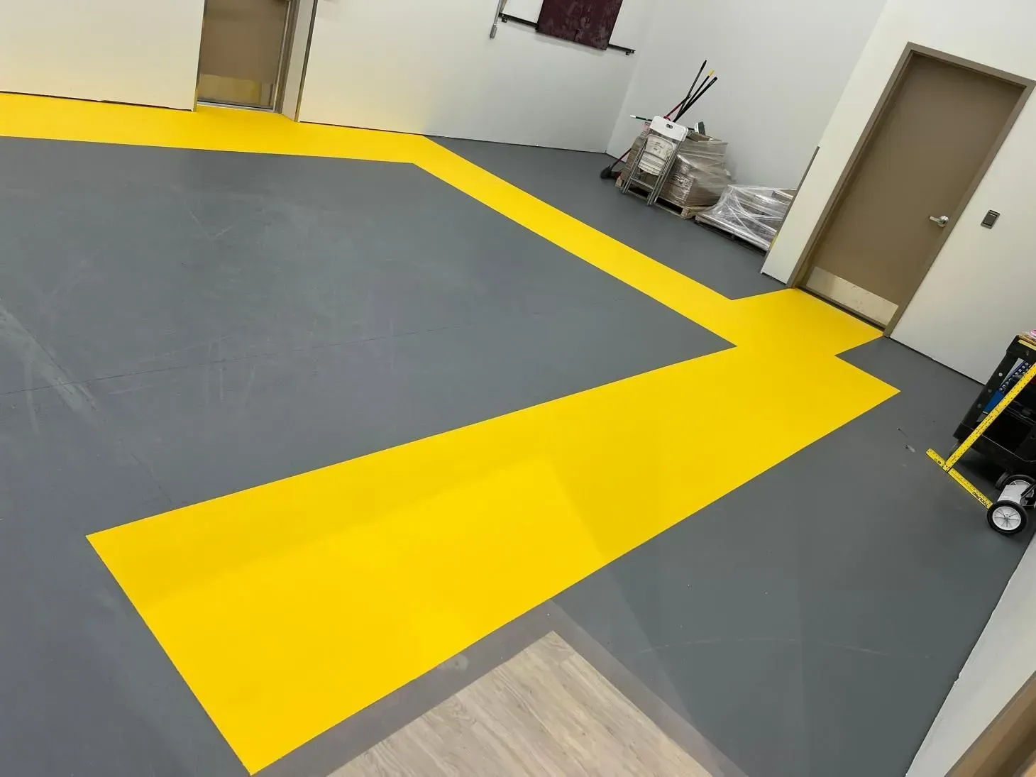 Grey floor with yellow painted pathways in a commercial space, near doors and equipment.