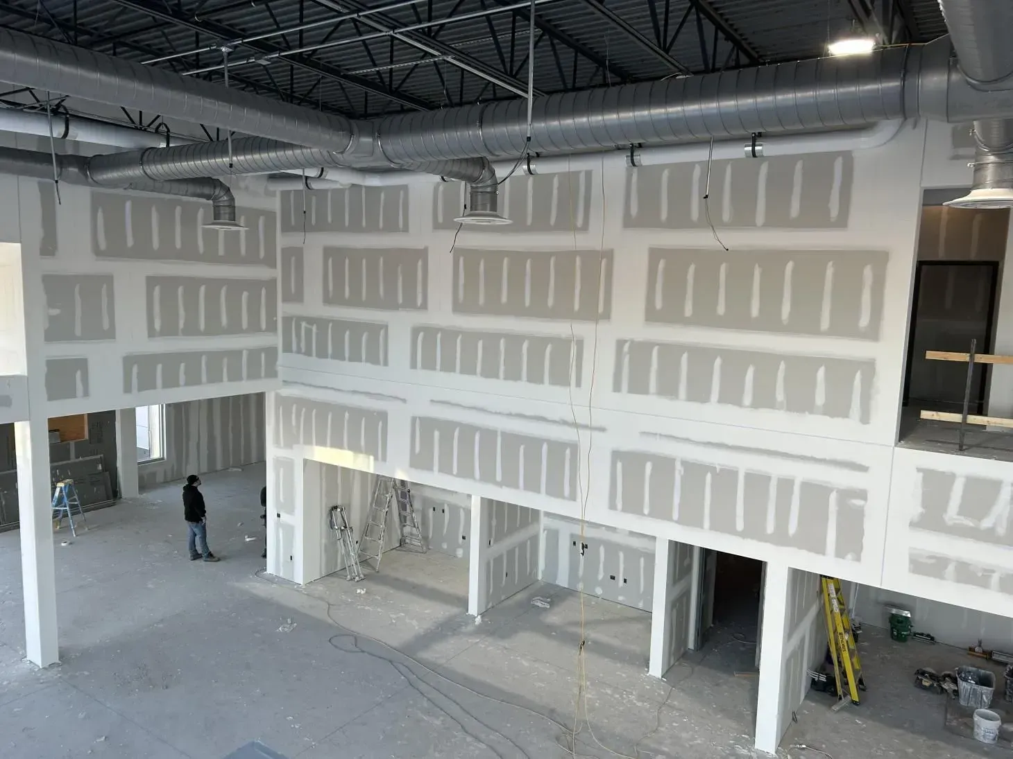 Interior construction site with drywall installed. Person standing.