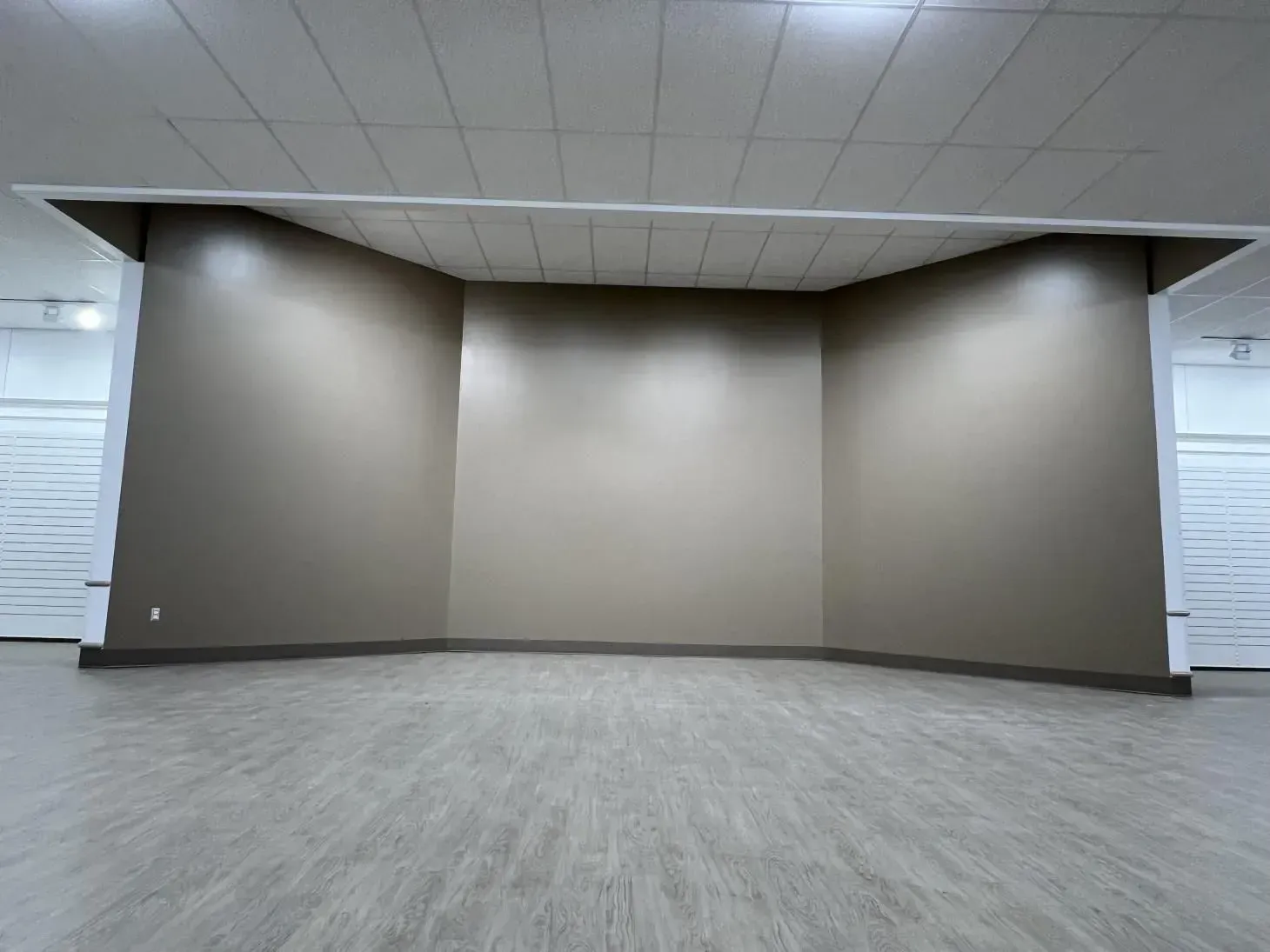 Empty room with a curved stage area, painted in shades of gray. The floor is light gray.
