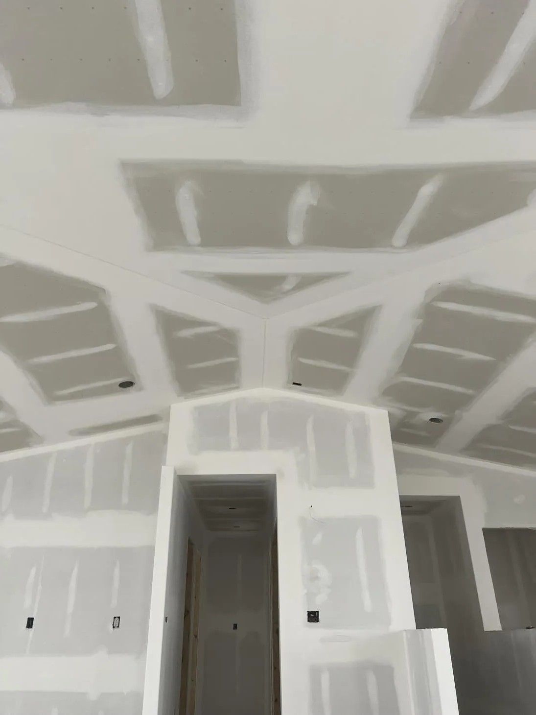 Drywall installed on a vaulted ceiling in a building under construction.