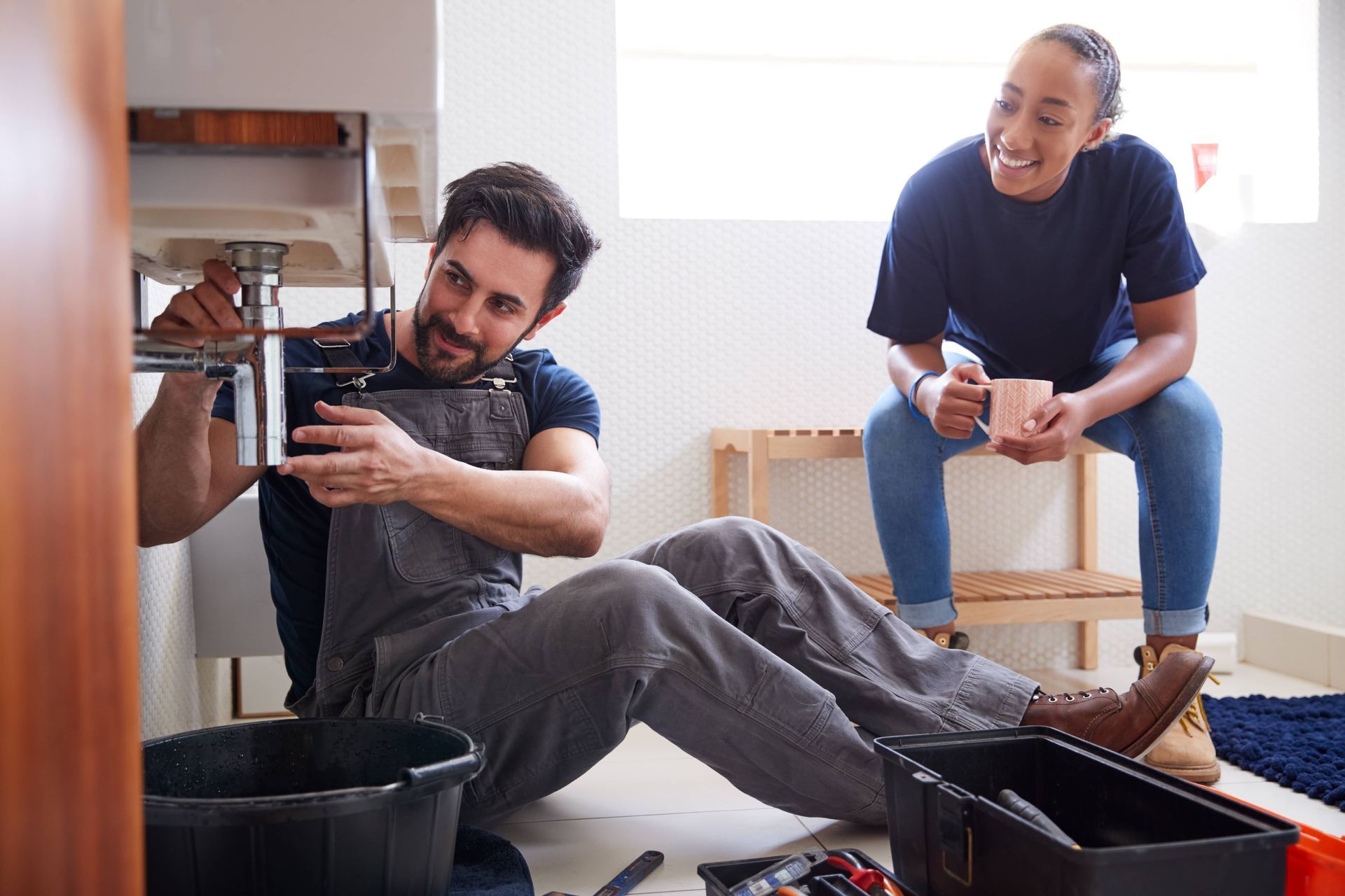 Male plumber teaching female apprentice to fix issues for EDM Home Services