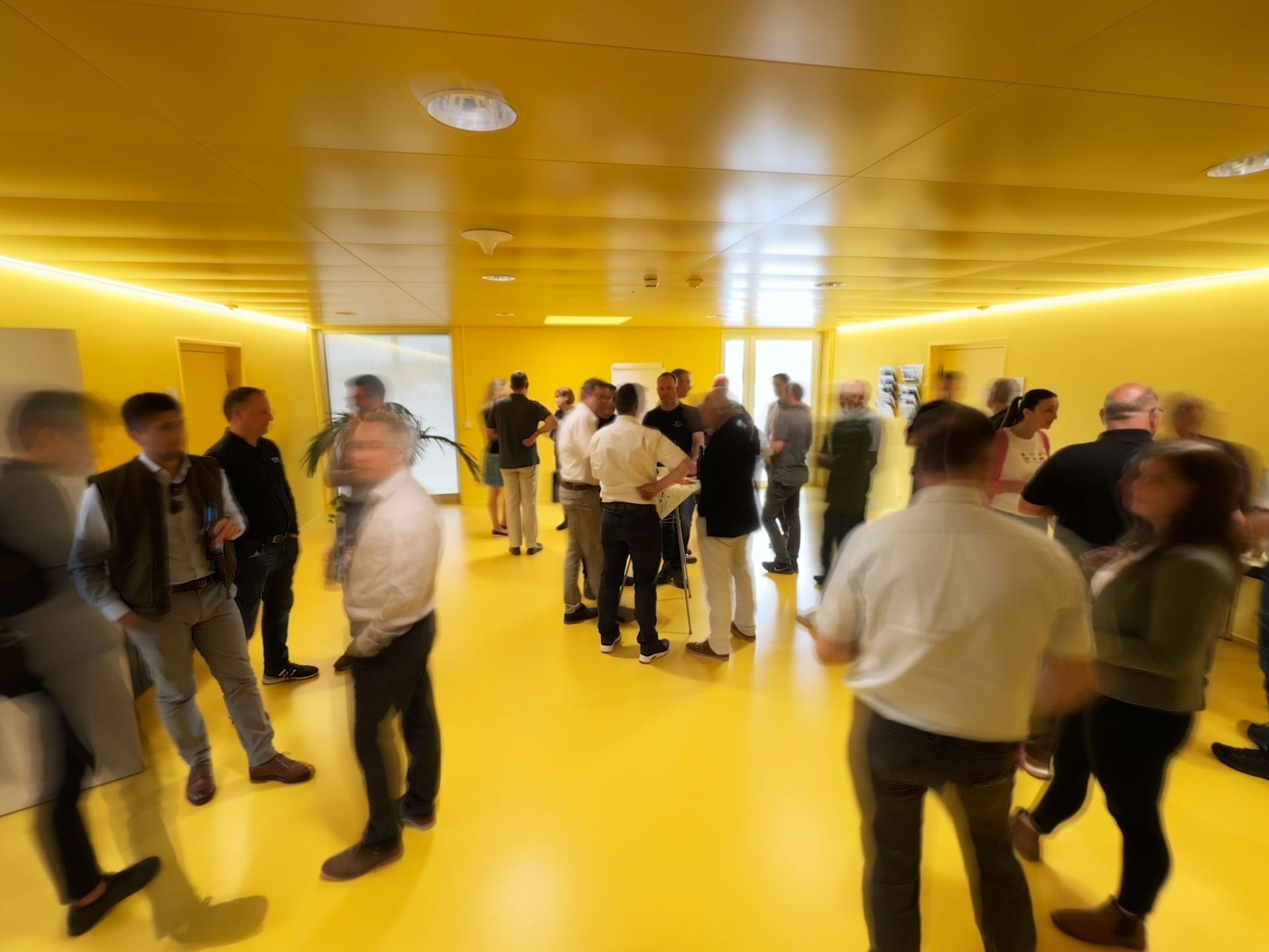 Eine Gruppe von Menschen steht in einem Raum mit gelben Wänden