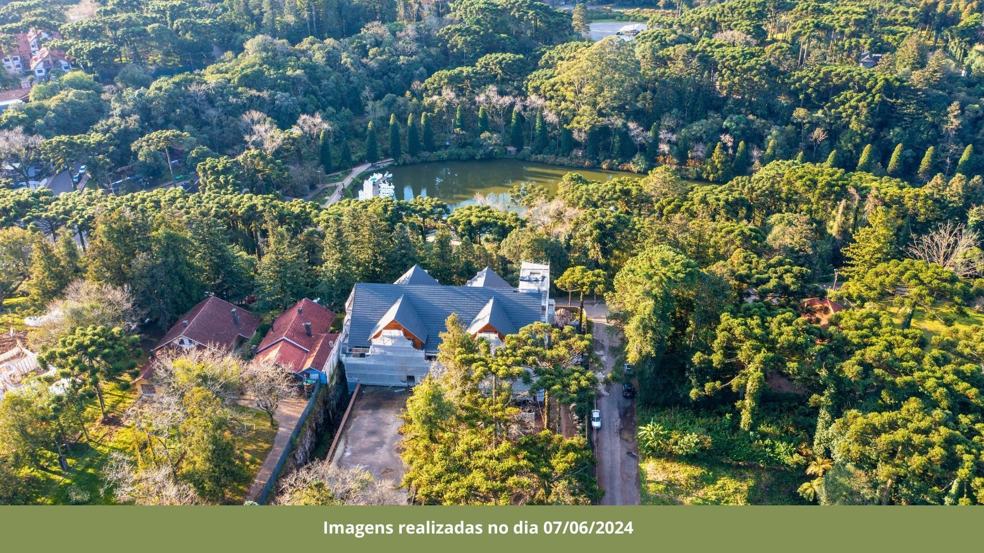 Uma vista aérea de uma casa cercada por árvores e um lago.