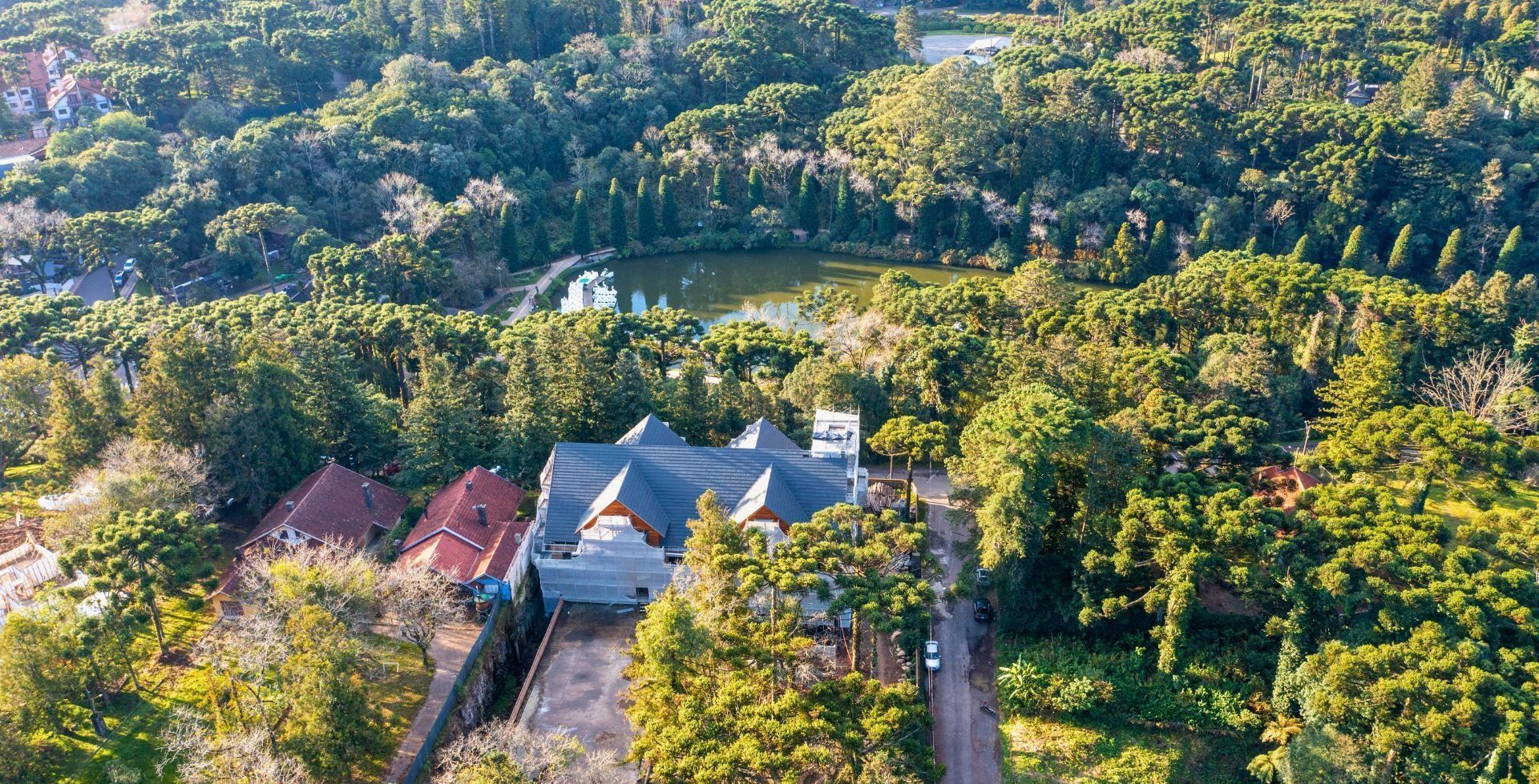 Uma vista aérea de uma casa cercada por árvores e um lago.