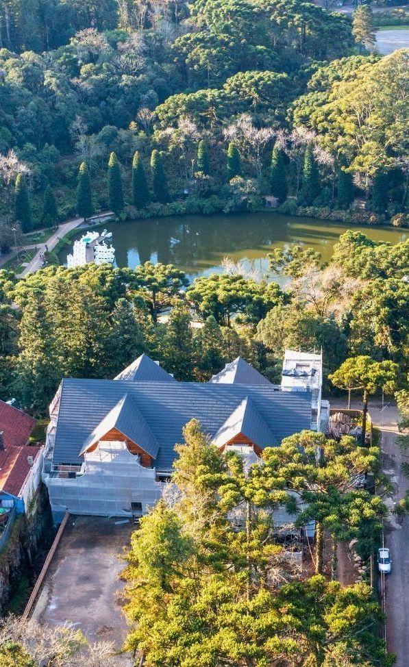 Uma vista aérea de uma casa cercada por árvores e um lago.