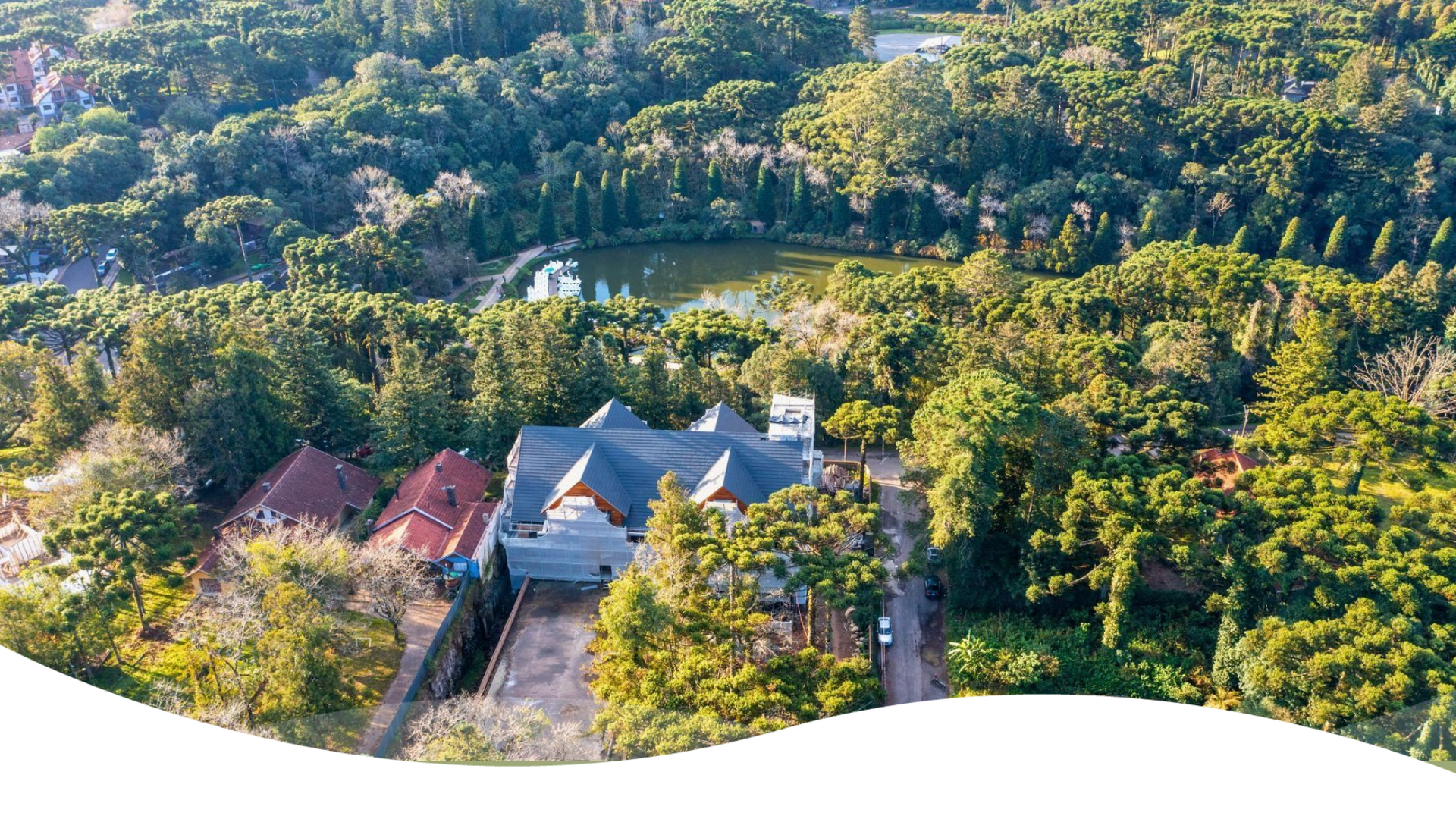 Uma vista aérea de uma casa cercada por árvores e um lago.