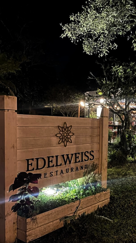 Uma placa de madeira do restaurante edelweiss fica acesa à noite.