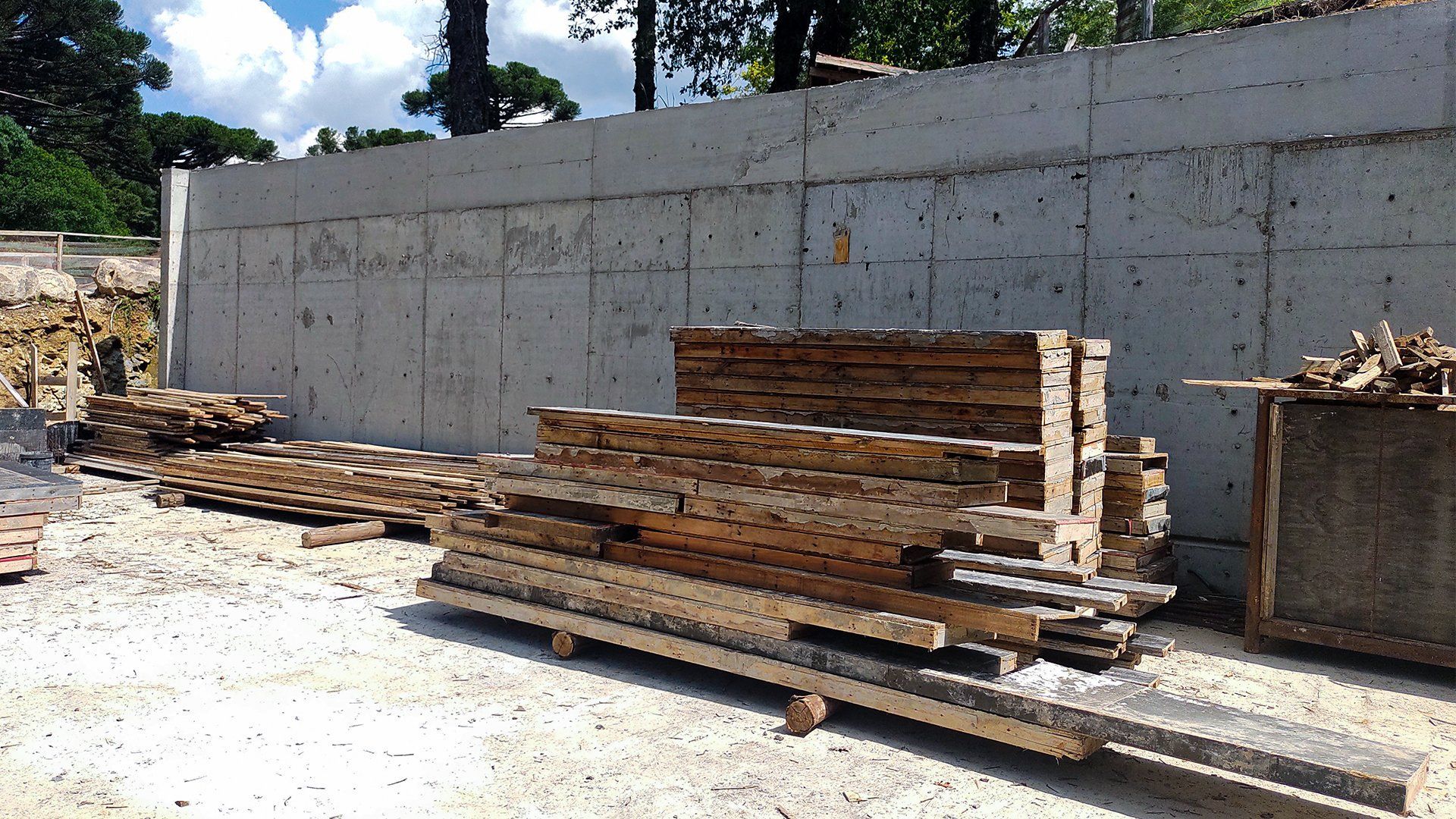 Uma pilha de madeira está em frente a uma parede de concreto