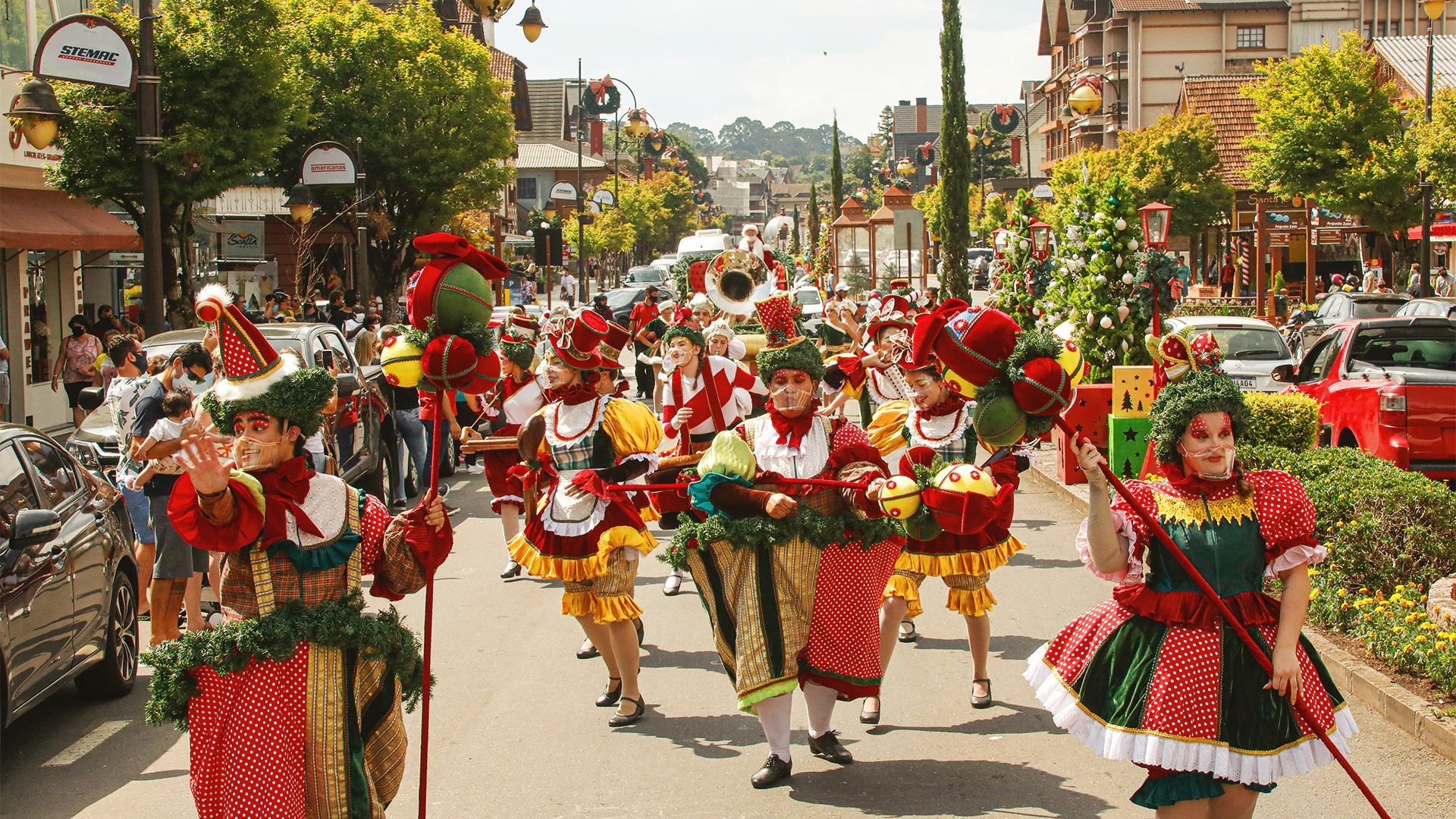 Um grupo de pessoas em trajes coloridos marcha pela rua.