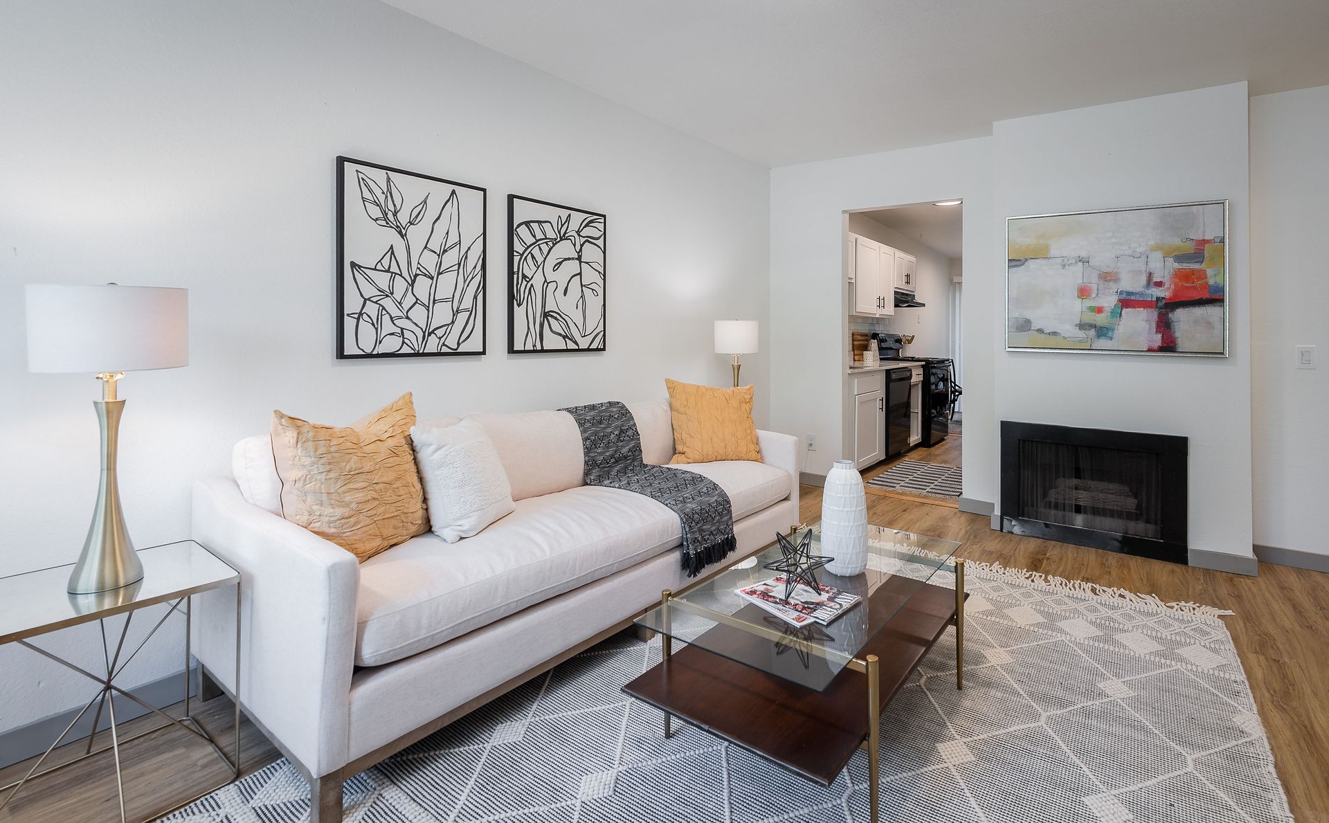 Living room with white sofa, art, lamps, and a view into the kitchen.