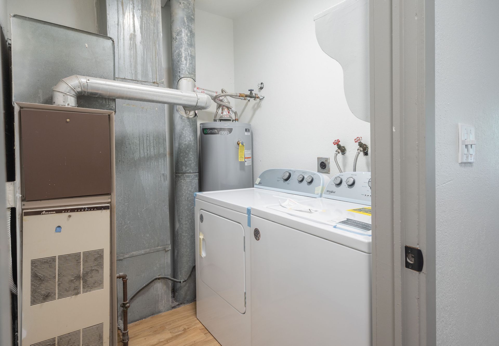 Laundry room with white washer and dryer, water heater, and furnace.