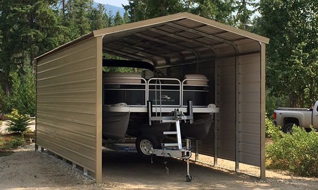 A pontoon boat is parked in a metal carport.