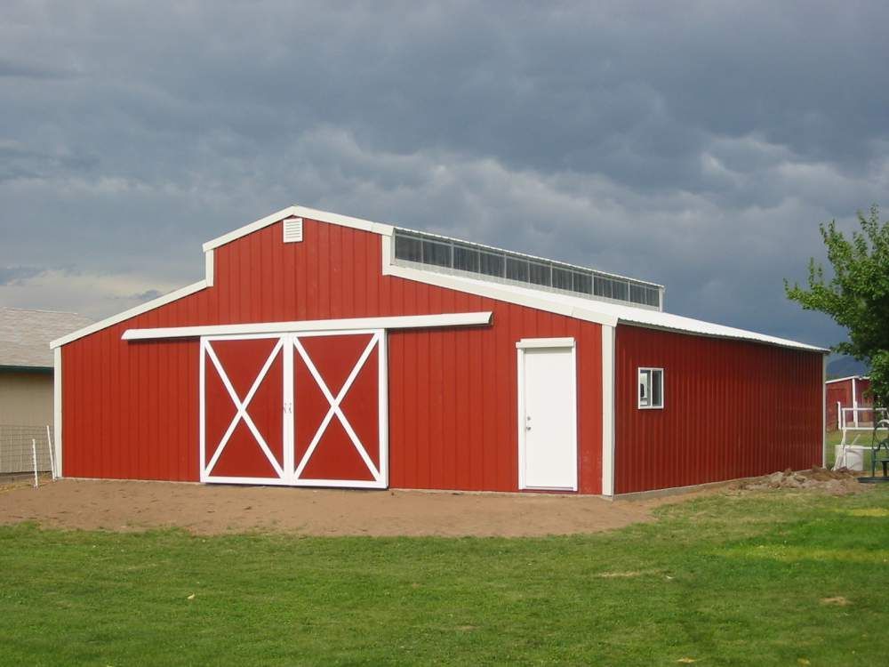 A red horse barn with white trim and sliding doors by Metal-Built Buildings Canada