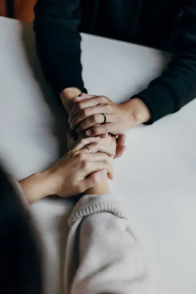 Hands stacked together in a supportive group gesture on a light surface