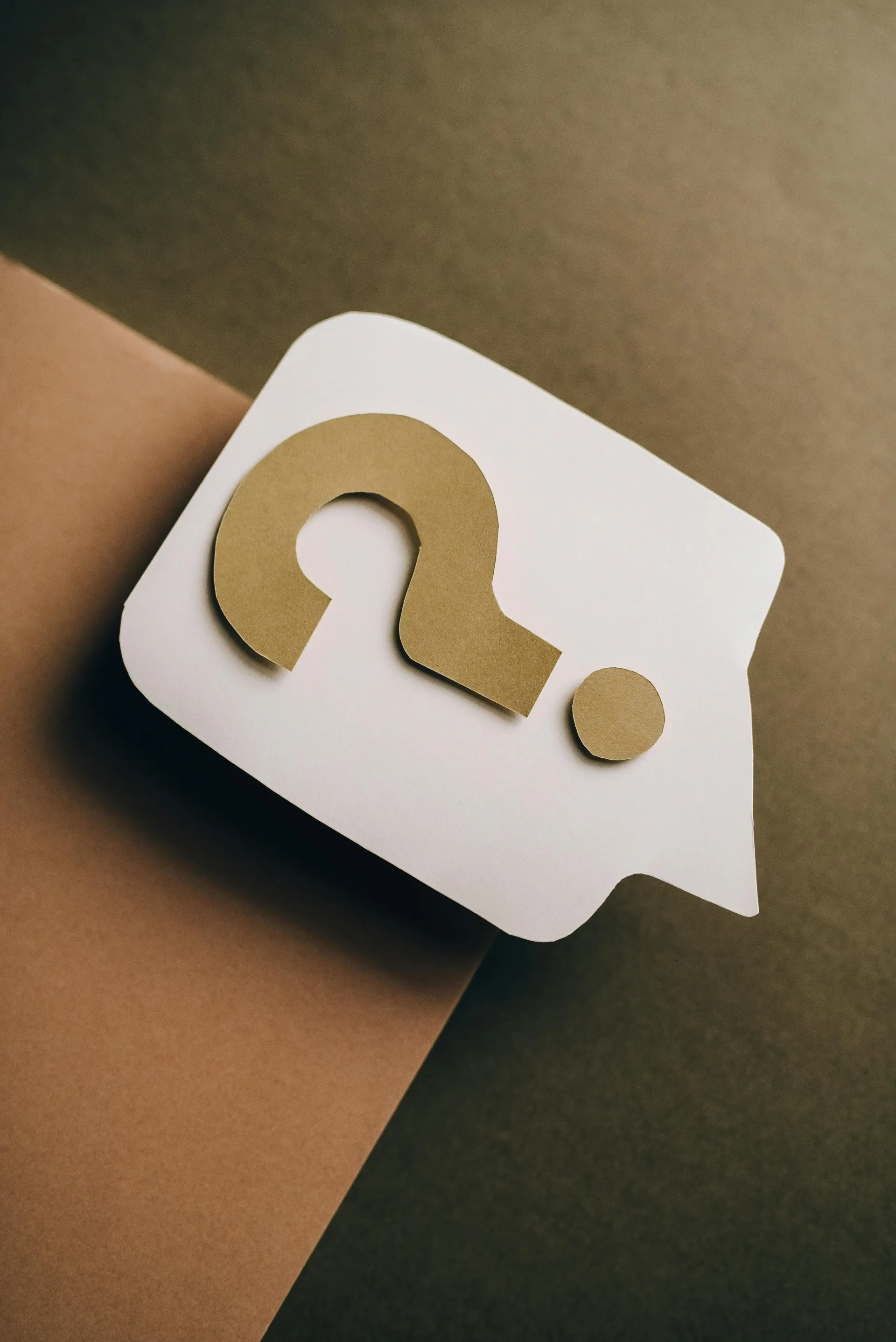 White speech bubble icon with a gold question mark on a brown and olive background