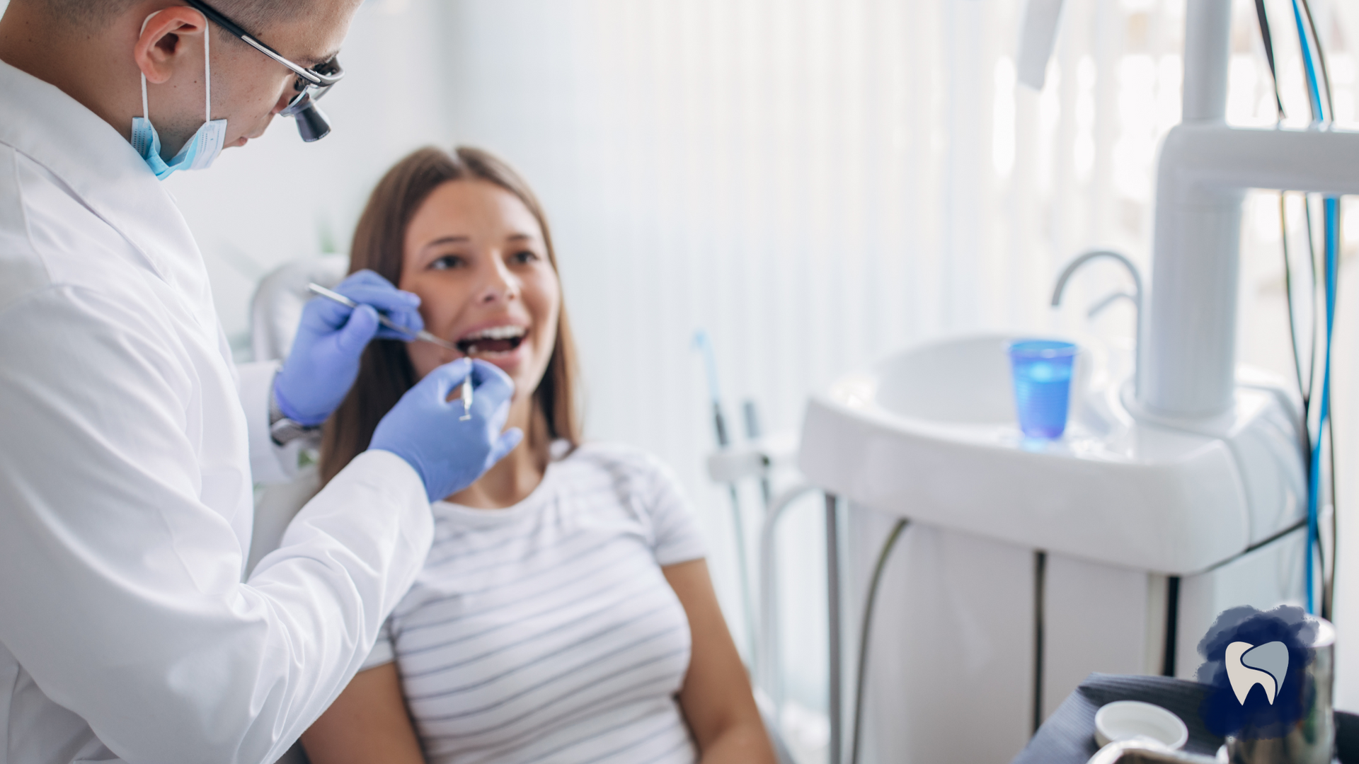 Dentist examining a patient's teeth in a dental office. Patient smiles; dentist uses tools.