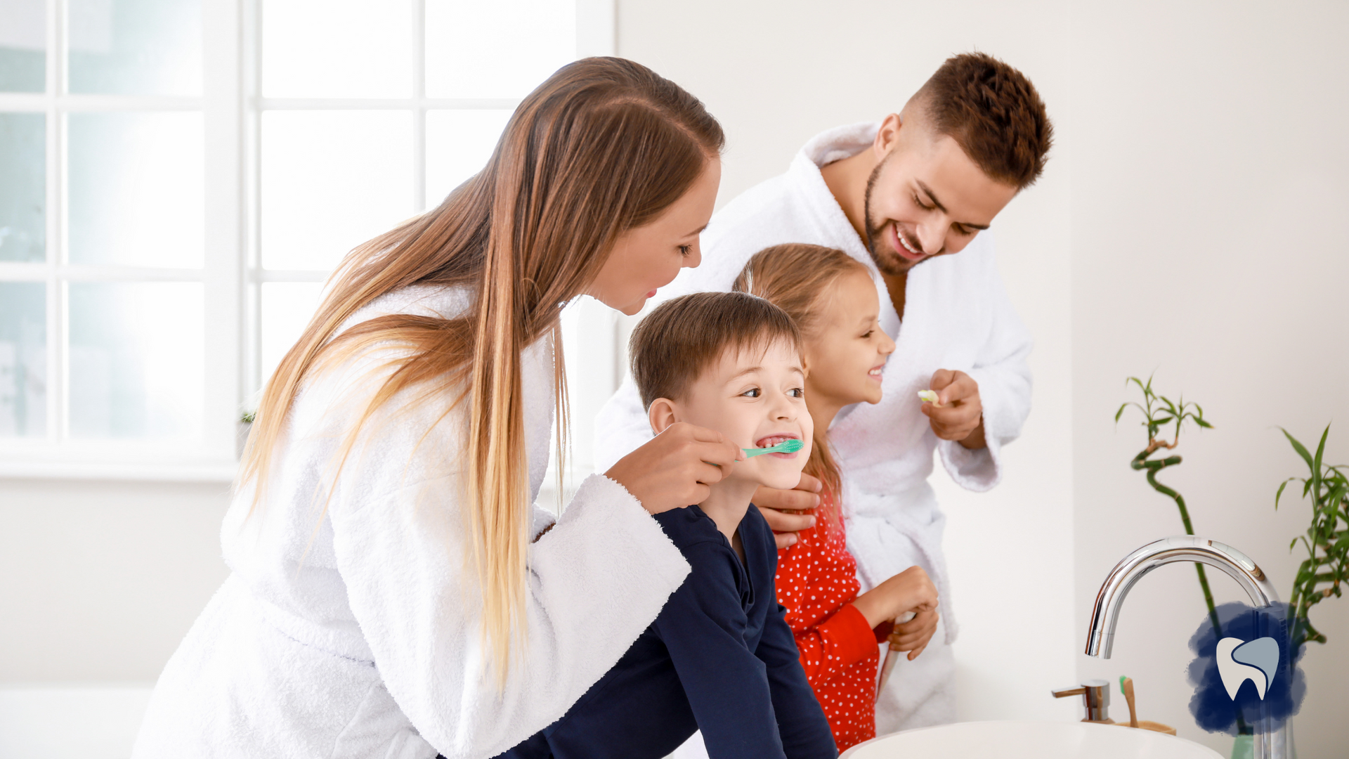 Family in white bathrobes brushing their teeth in bathroom.