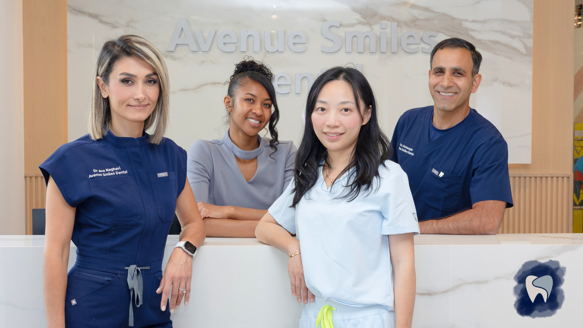 Four people smiling at a dental office reception desk.