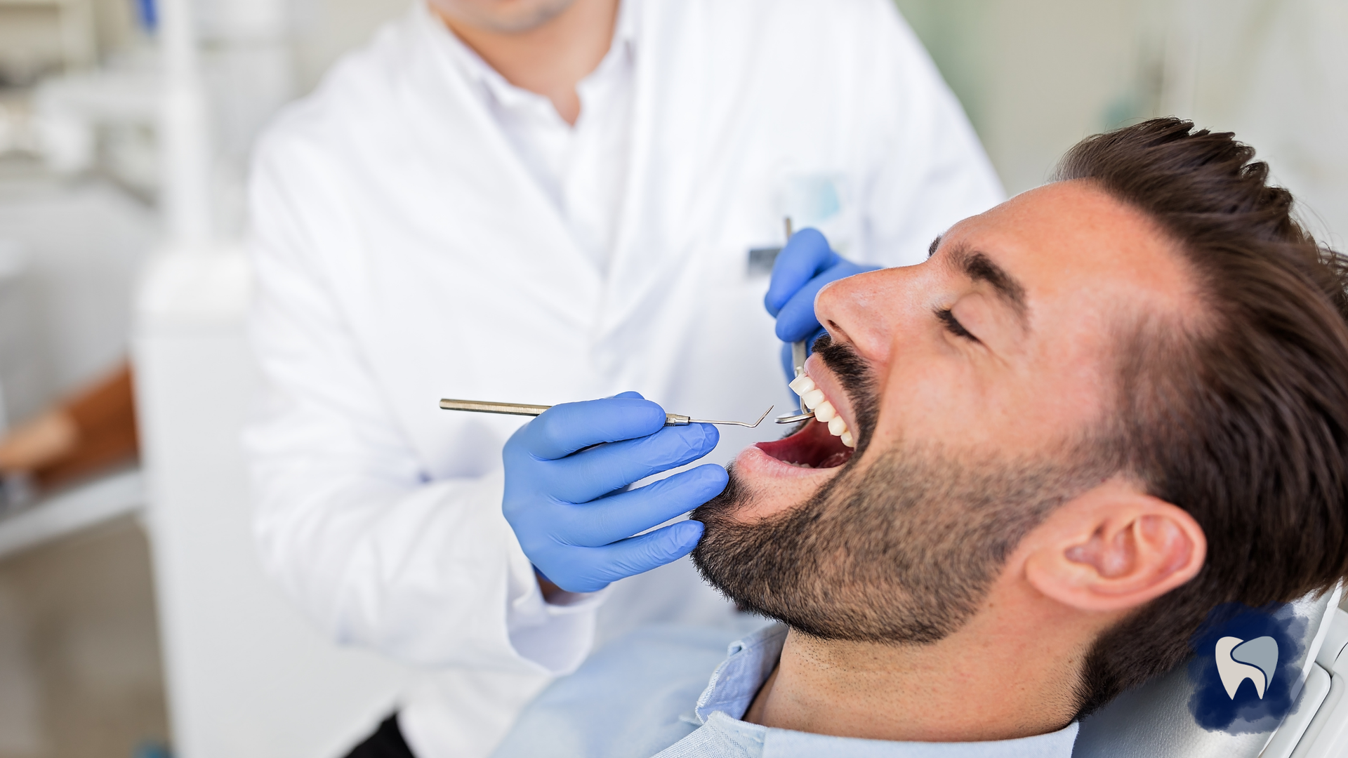 Dentist examining a patient's open mouth with an instrument in a dental clinic.