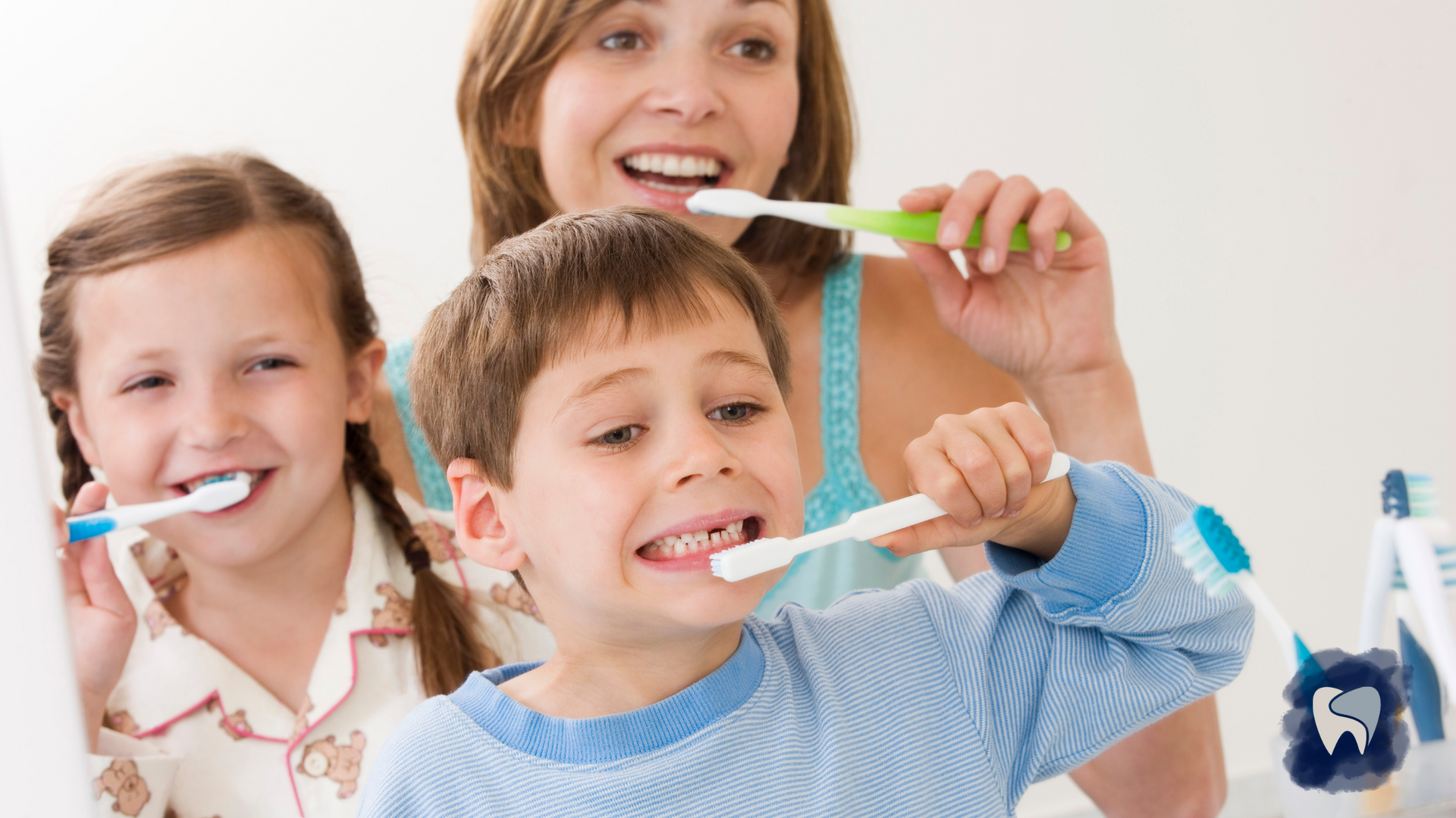 A woman and two children brushing their teeth in front of a mirror.