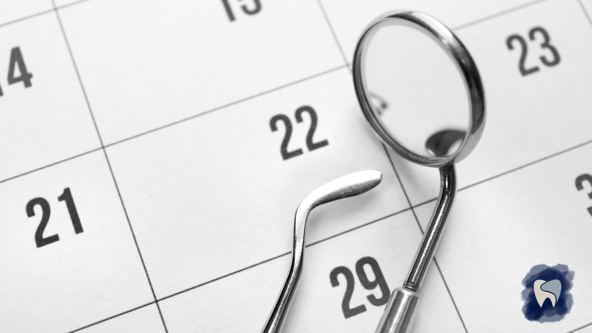 Dental mirror and pick resting on a calendar, focused on the date 22.