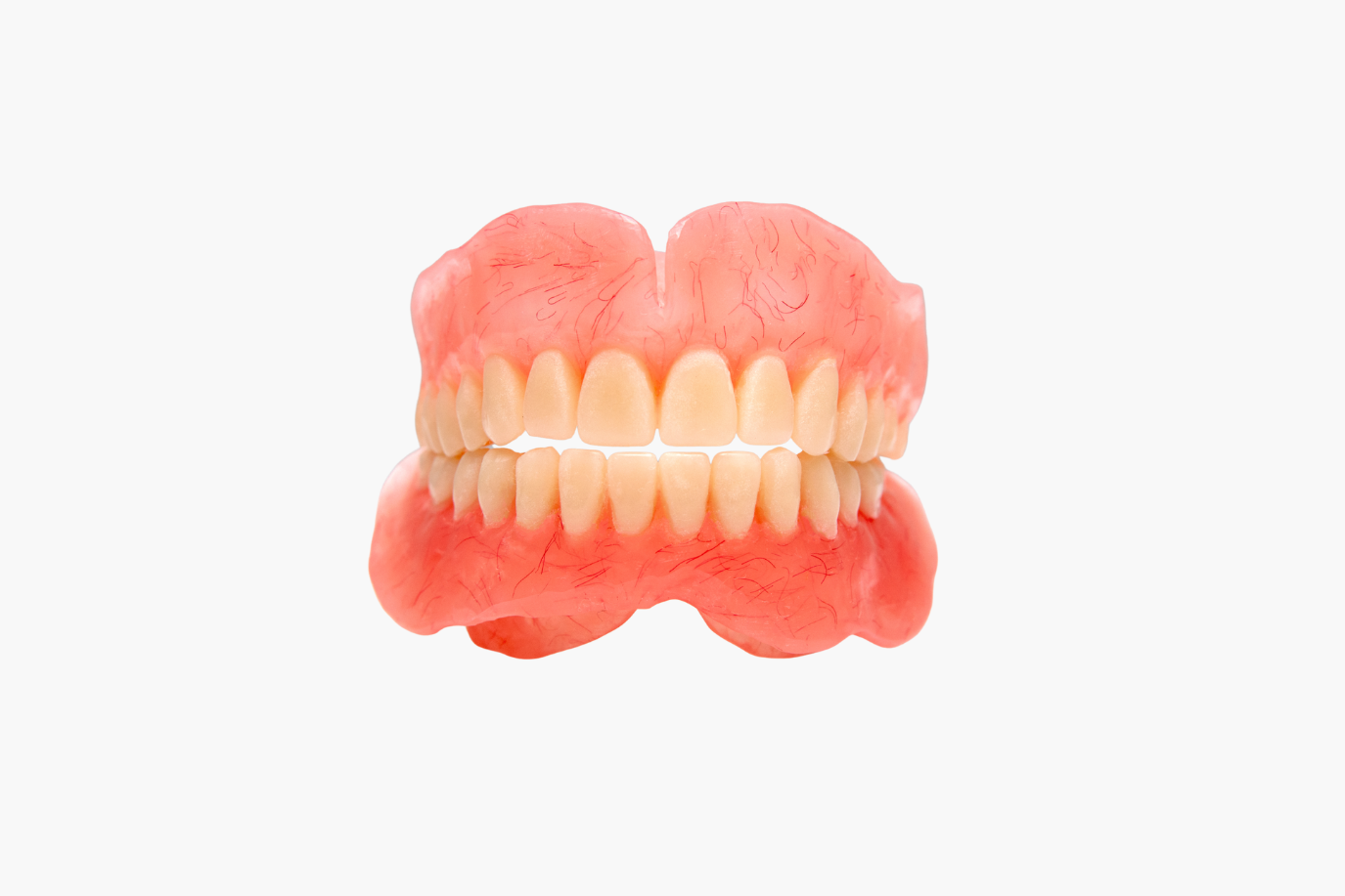 Set of dentures, upper and lower, with pink gum-colored base and rows of white teeth.