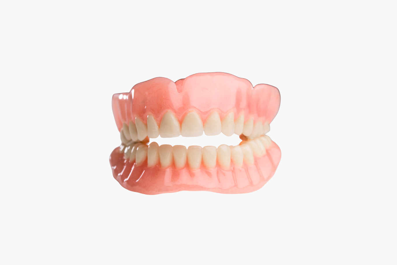 Set of upper and lower dentures, pink and white, isolated on white background.