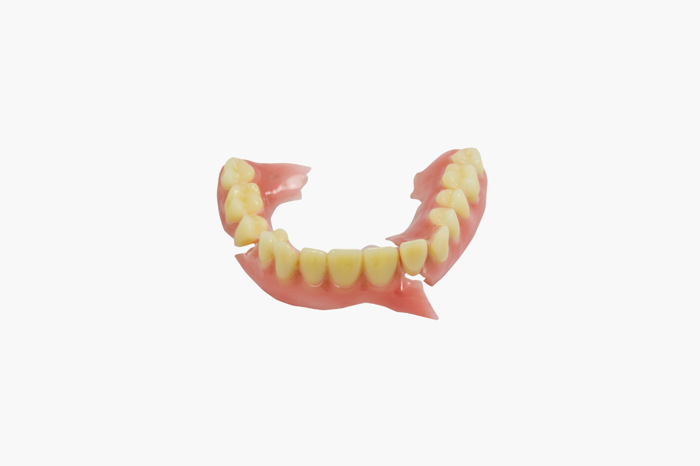 Broken upper dentures with pink base and yellow teeth.