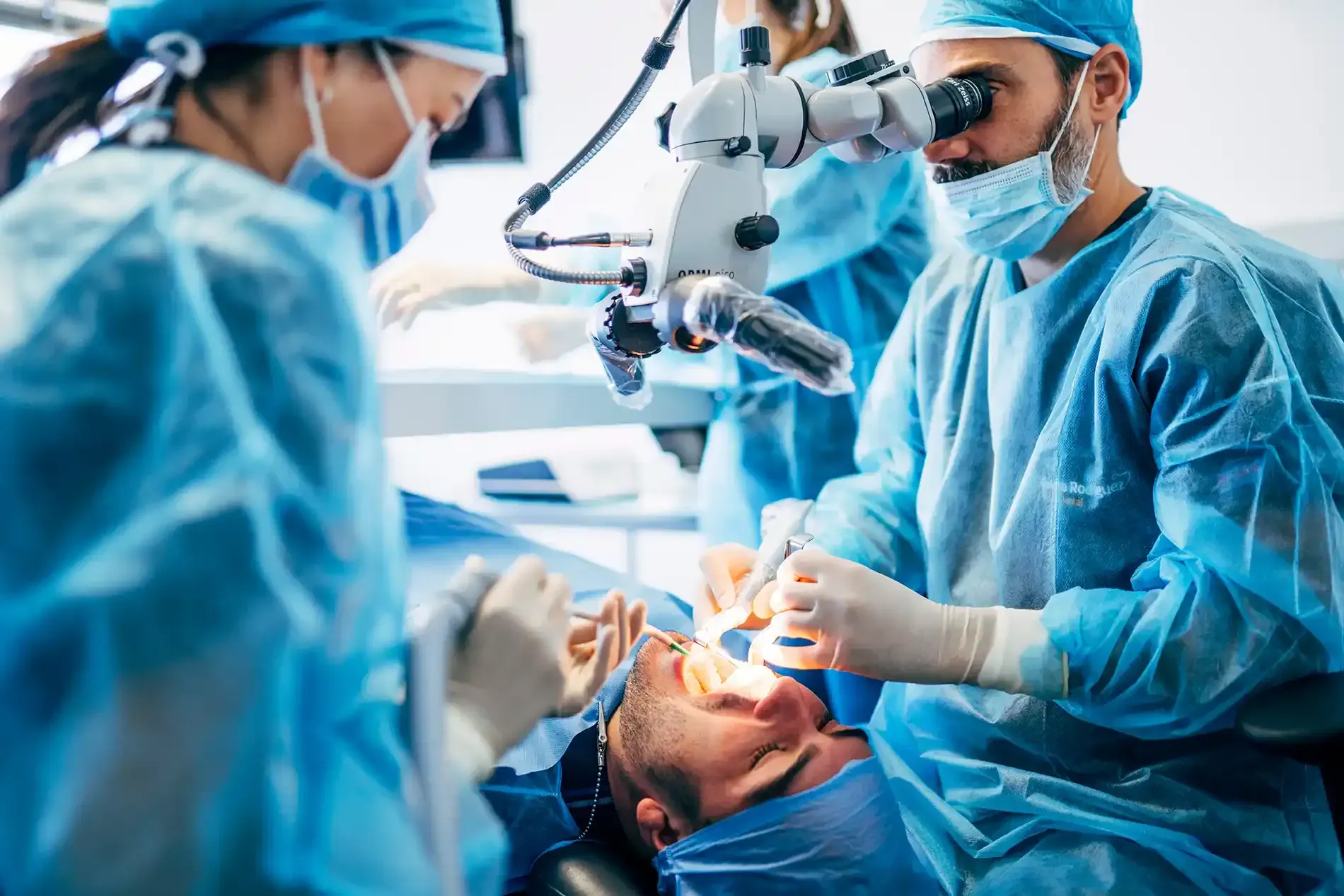 Surgeons in blue scrubs performing eye surgery on a patient in an operating room.