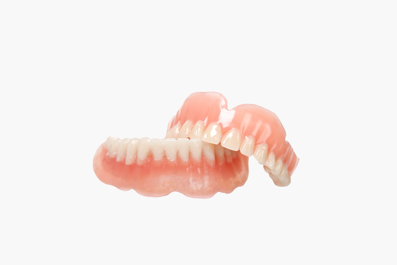 Set of upper and lower dentures, pink and white, on white background.
