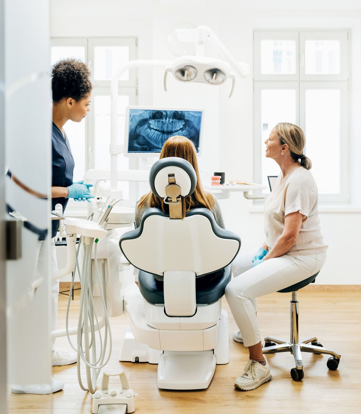 Dentist, assistant, and patient in a dental office examining an x-ray.