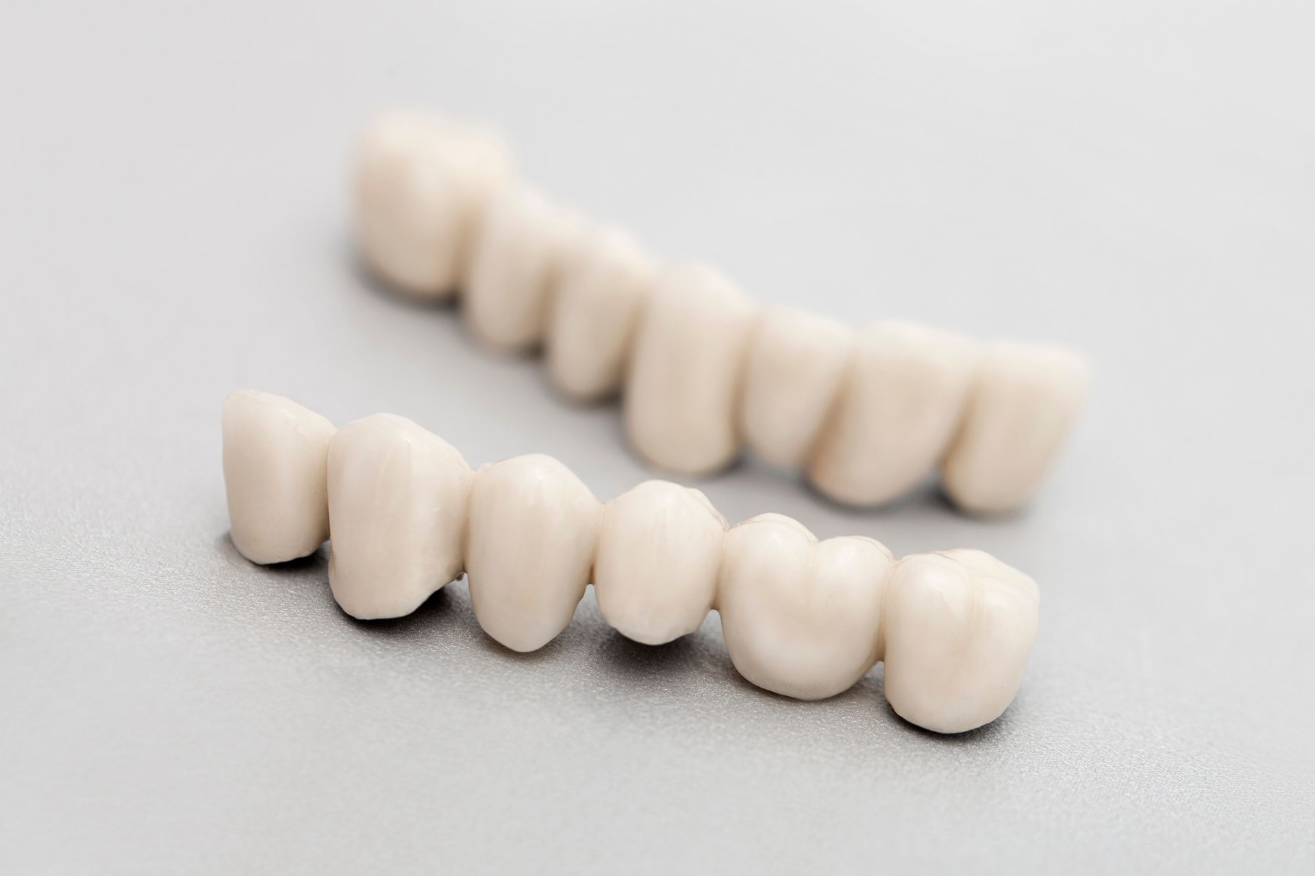 A pair of white teeth are sitting on a white surface.