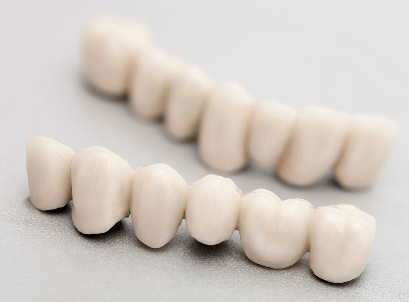 A pair of white teeth are sitting on a white surface.