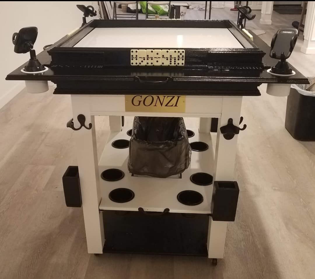 A custom-made game table with dominoes, drink holders, and phone mounts, in a home.